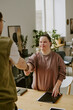 © AnnaStills - Vertical high angle shot of unrecognizable tall job interviewer shaking hands with applicant with down syndrome after successful interview