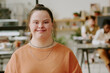© AnnaStills - Medium close up portrait of happy female office worker with down syndrome posing for photo in modern office