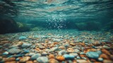 Underwater scene pebbles on riverbed, bubbles rising, water surface above