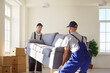 © Studio Romantic - Cheerful man movers carrying a sofa during a relocation to a new home. Moving service staff, teamwork, and the effort involved in transporting furniture for a smooth and efficient move.