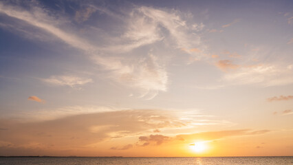 Wall Mural - sunset sky clouds over sea in the evening with orange, yellow sunlight on golden hour, horizon sea s