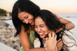 © Alberto Midnight/Stocksy - Two young women laughing and hugging on the beach at sunset