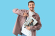 © Pixel-Shot - Young man pointing at magazines on blue background