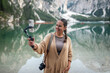 © Lupe Rodriguez/Stocksy - woman using mobile phone at braies lake in the dolomites