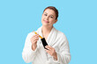 © Pixel-Shot - Beautiful young woman putting in case  facial massage tool on blue background