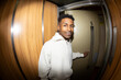 © Jimena Roquero/Stocksy - Portrait in elevator of young man smiling at camera. Fisheye