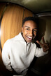 © Jimena Roquero/Stocksy - Portrait in elevator of young man smiling at camera. Fisheye