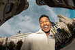 © Jimena Roquero/Stocksy - Fisheye. Modern portrait of man in city street smiling at camera