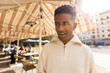 © Jimena Roquero/Stocksy - Man in street by restaurant terrace in sunlight