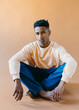 © Jimena Roquero/Stocksy - Studio portrait of young man sitting on the floor looking at camera