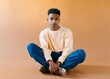 © Jimena Roquero/Stocksy - Studio portrait of young man sitting on the floor looking at camera