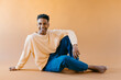 © Jimena Roquero/Stocksy - Studio portrait of young man sitting on the floor smiling at camera
