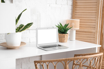 Wall Mural - stylish table with laptop and houseplants near white brick wall in room