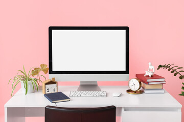 Wall Mural - modern workplace with blank computer monitor, alarm clock and plant on pink background