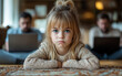 © Dmitriy - A little girl sits crying while playing with her doll, feeling lonely. In the background, her parents are absorbed in their phones and laptops, ignoring her distress.