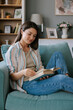 © Mihajlo Ckovric/Stocksy - Relaxed Woman Reading a Book on a Cozy Couch at Home