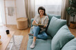 © Mihajlo Ckovric/Stocksy - Relaxed Woman Reading a Book on a Cozy Couch at Home