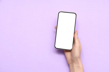 Wall Mural - female hand with mobile phone on purple background