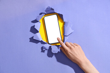 Wall Mural - female hand with mobile phone visible through hole in color paper