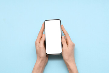 Wall Mural - female hand with mobile phone on blue background