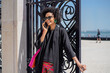 © tessy morelli/Stocksy - Stylish traveler smiling on phone call holding suitcase