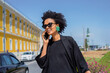 © tessy morelli/Stocksy - Woman on phone call by the street in Lisbon