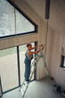 © Alina Hvostikova/Stocksy - Woman performing repairs on a ladder in a construction area