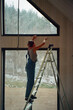 © Alina Hvostikova/Stocksy - Builder repairing a window in a snowy landscape