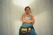 © Alina Hvostikova/Stocksy - LGBTQ builder smiles during construction repairs in renovated space