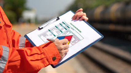 Wall Mural - action of an engineer is checking on the chemical hazard material form with background of crude oil 