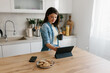 © Mihajlo Ckovric/Stocksy - Woman Enjoying Coffee While Browsing on a Tablet in Modern Kitchen