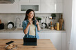© Mihajlo Ckovric/Stocksy - Young Woman Drinking Coffee While Working on a Tablet in a Kitchen