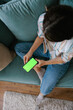 © Mihajlo Ckovric/Stocksy - Woman Relaxing on Couch Using Smartphone with Green Screen Display