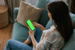 © Mihajlo Ckovric/Stocksy - Woman Relaxing on Couch Using Smartphone with Green Screen Display