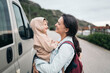 © Santi Nuñez/Stocksy - Mother holding smiling son next to minivan on road trip