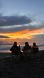 © Alina Hvostikova/Stocksy - Gathering at sunset on the beach with friends enjoying the view