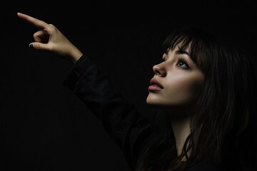 Poster - A woman points at something on a black background, perfect for illustrating a concept or highlighting a key point