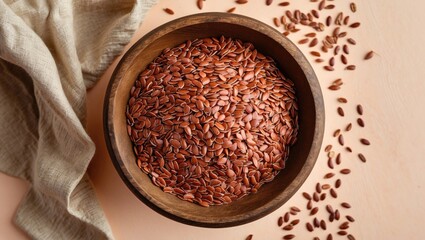 Aufkleber - Brown flax seeds in a wooden bowl centered against a soft pastel peach background with scattered seeds and a light linen cloth beside it.