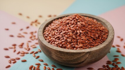Aufkleber - Brown flax seeds heaped in a wooden bowl centered on a pastel blue and pink background with scattered seeds around the bowl