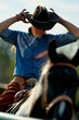© Connect Images - Cowboy adjusts hat while sitting on a horse, showcasing Western lifestyle and attire. Brandenburg, Germany