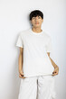 © Jimena Roquero/Stocksy - Androgynous person showing white t-shirt posing over white wall