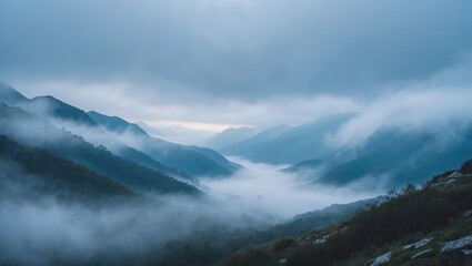 Aufkleber - Misty blue mountains under a cloudy sky with soft fog rolling through a deep valley creating a serene and tranquil landscape scene