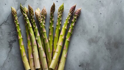 Poster - Fresh organic asparagus arranged on a gray concrete background from a top view perspective with ample empty space for text or design elements.