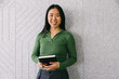 © VICTOR TORRES/Stocksy - Young professional woman holding notebook and smiling confidently