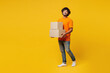 © ViDi Studio - Full body young smiling fun cool happy Indian man he wear orange t-shirt casual clothes hold stack of two blank cardboard boxes isolated on plain yellow background studio portrait. Lifestyle concept.