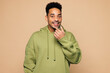 © ViDi Studio - Young man of African American ethnicity wears green hoodie casual clothes hold in hand invisible transparent aligners, invisalign dental braces isolated on plain beige background. Lifestyle concept.