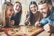 © whitestorm - A group of friends laughing heartily while playing a board game together in a cozy, well-lit room, enjoying each other's company and having a great time indoor.