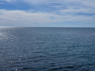 Wall Mural - shiny blue sea and sky with soft clouds