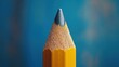 © Firadoaw - A close-up reveals a sharpened yellow pencil, its point honed to perfection, poised on a vibrant blue surface, ready to capture thoughts and ideas onto the page or canvas.