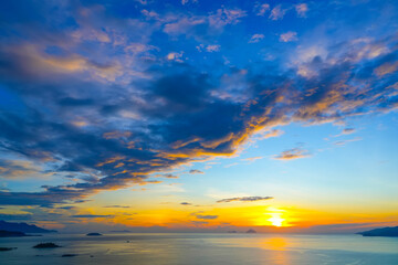 Wall Mural - View of horizon over ocean in the distance there are islands and mountains with lilac tinted clouds texture before sunrise early in the morning